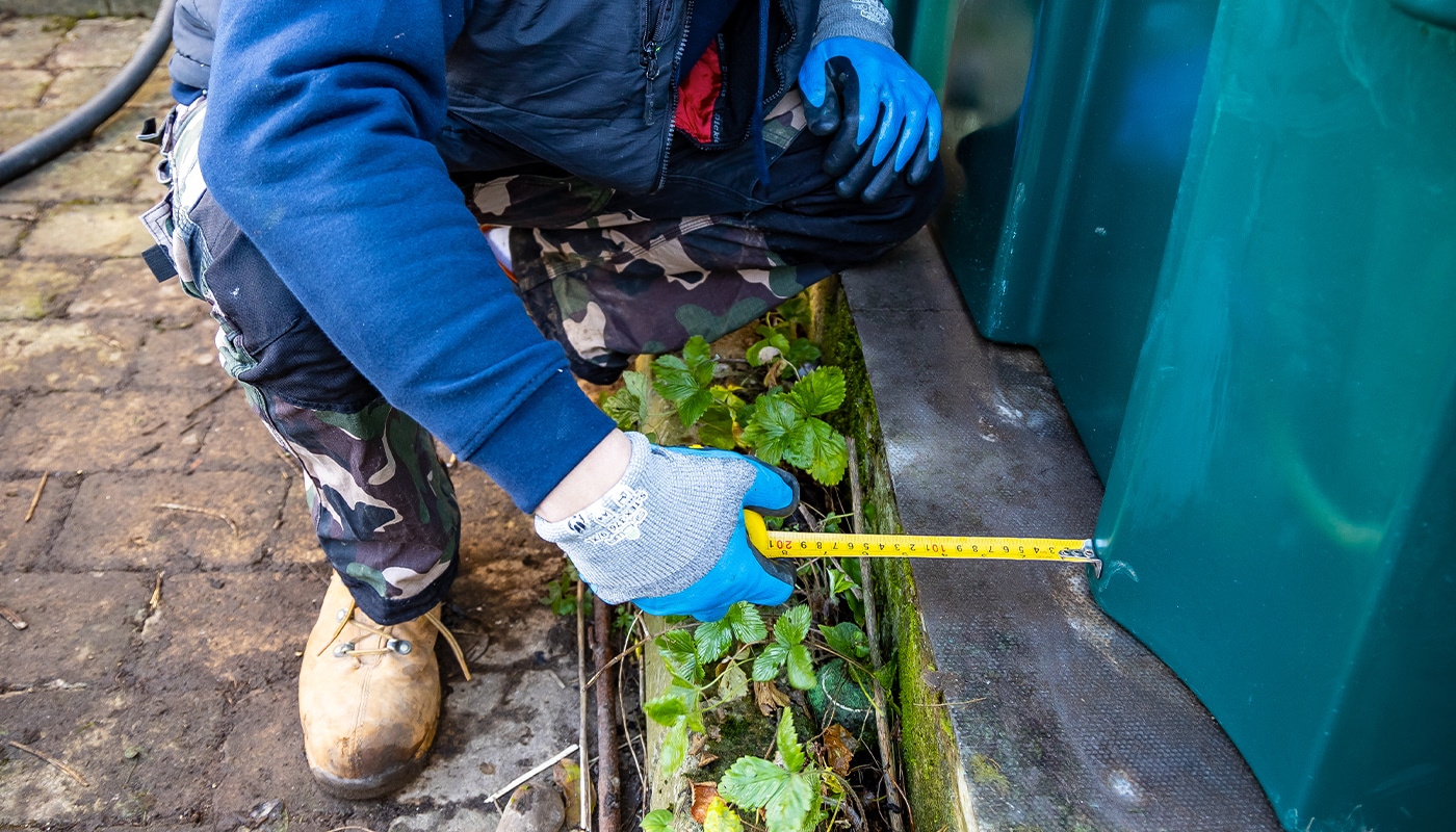 an engineer measuring an oil tank base to make sure oil tank installation regulations are being met