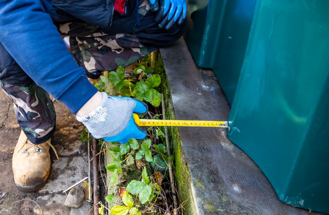 An oil tank engineer measuring a base to make sure Oil Tank Installation Regulations are being met